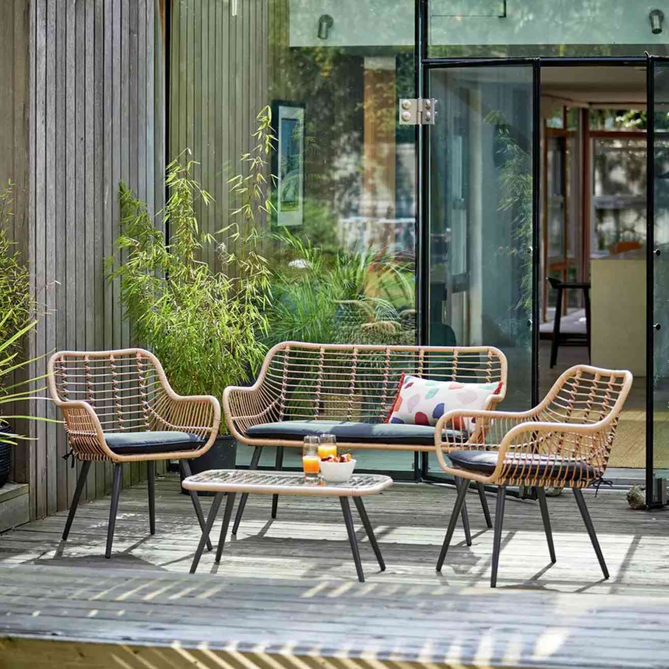 An outdoor woven seating set with separate chairs and a sofa, illustrating the delicate weave discussed in the pressure-washing caution.