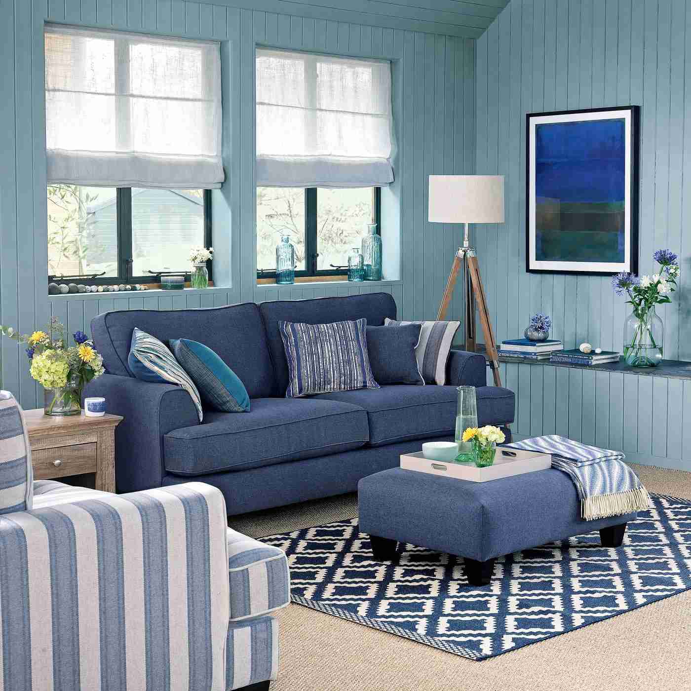 A blue sofa and upholstered footstool in a blue living room, used as an upholstery illustration in the source stain-removal guide.