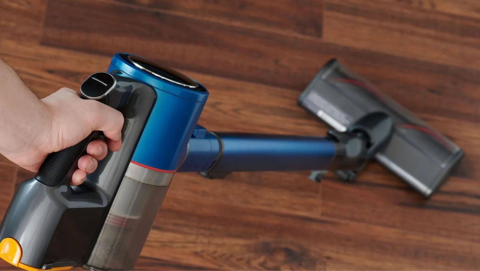 A cordless vacuum being used on a wood floor, illustrating the dry debris-removal stage in the source.