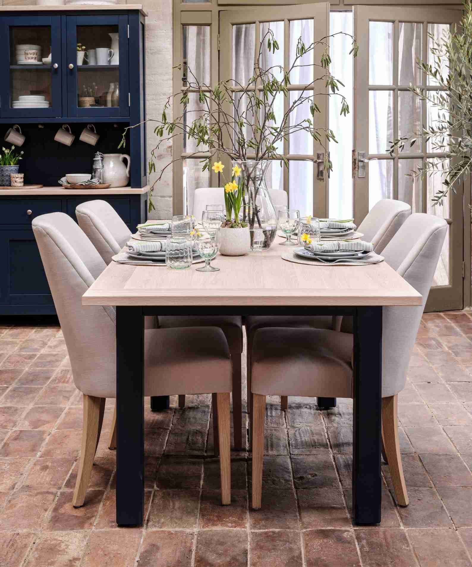 Upholstered dining chairs arranged around a set table, illustrating the fabric seats discussed in the source care guide.