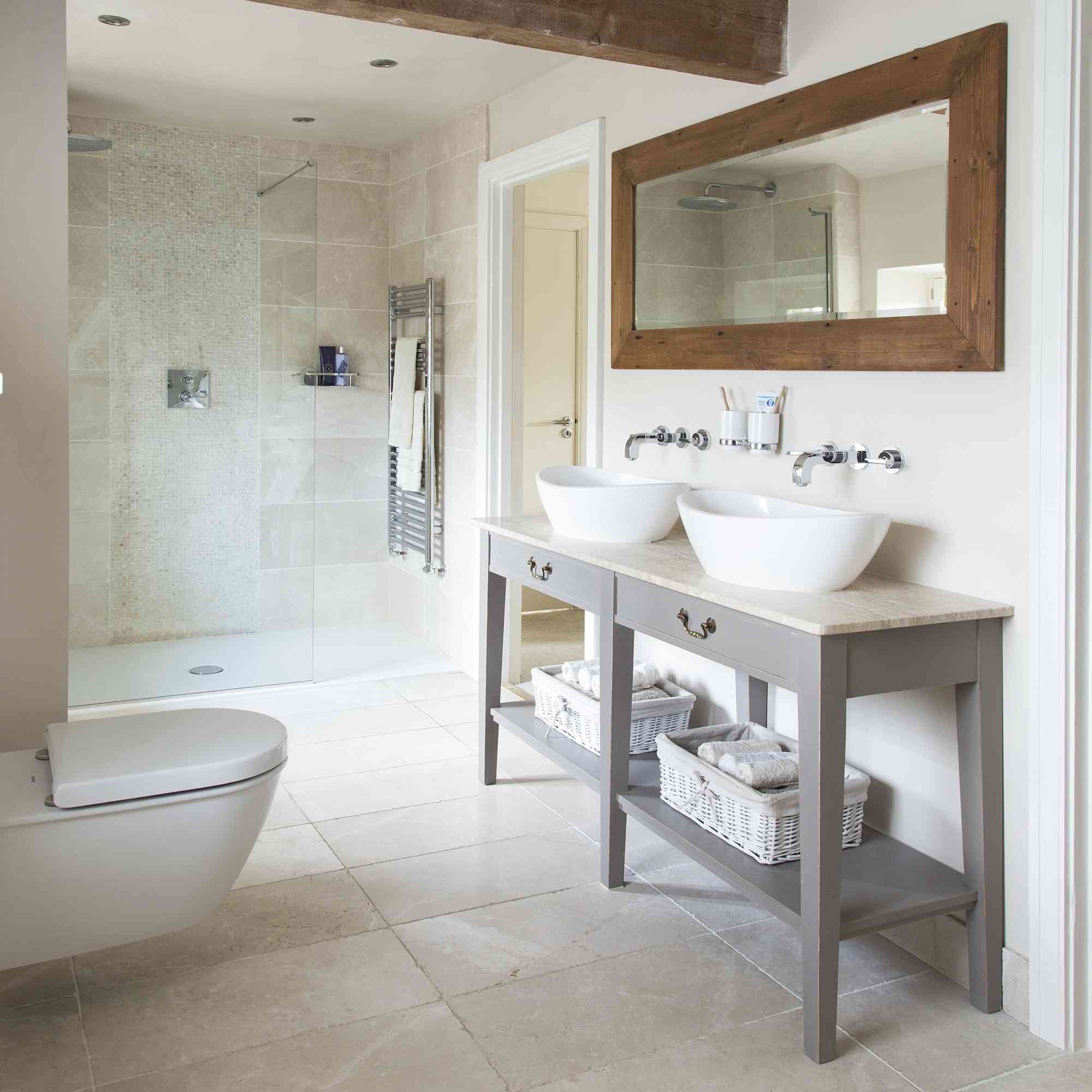A bathroom with pale stone tiles around the shower and on the floor, illustrating the material-specific care discussion in the source.