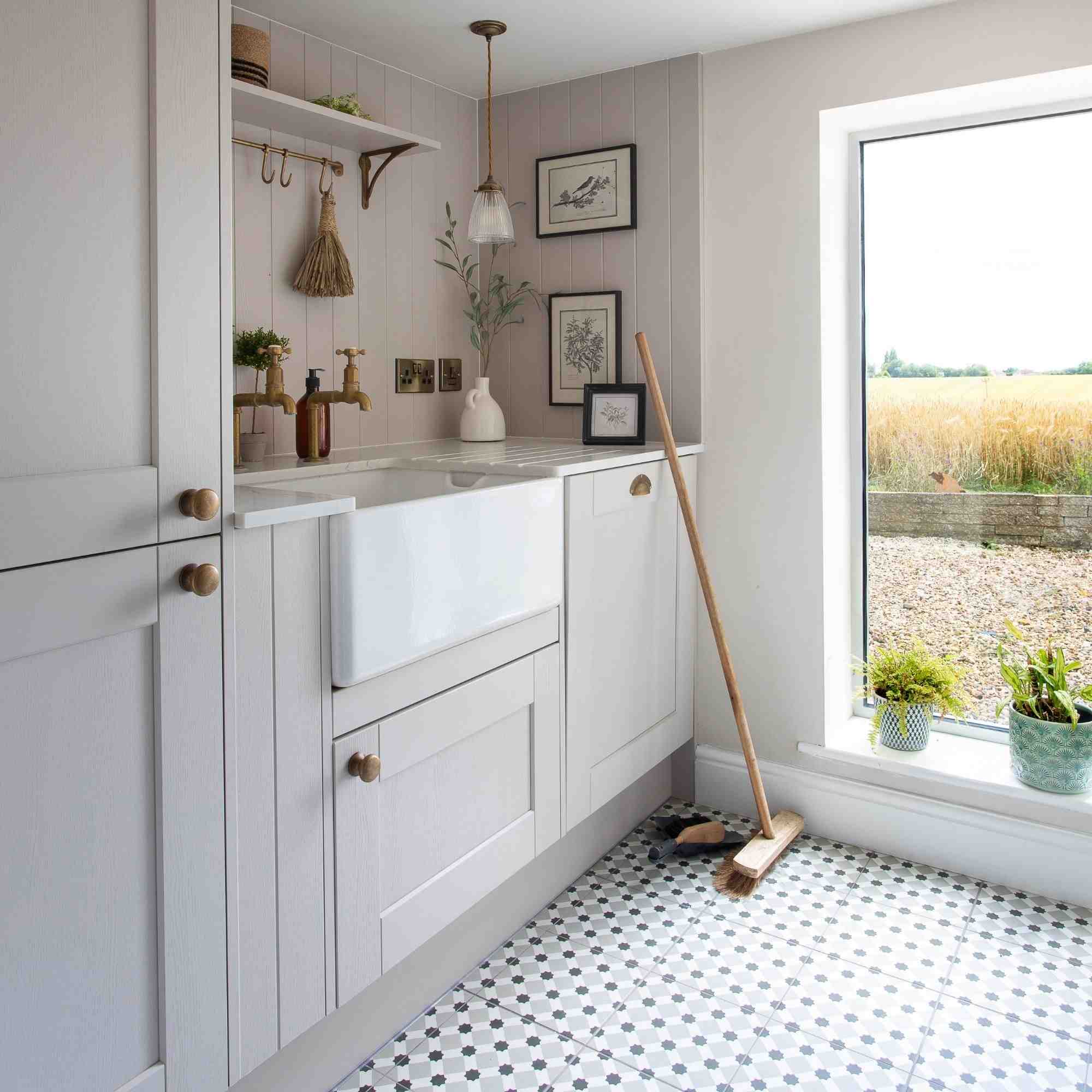 A utility room with a patterned tiled floor and a broom and dustpan beside the window, as illustrated in the source floor-cleaning discussion.