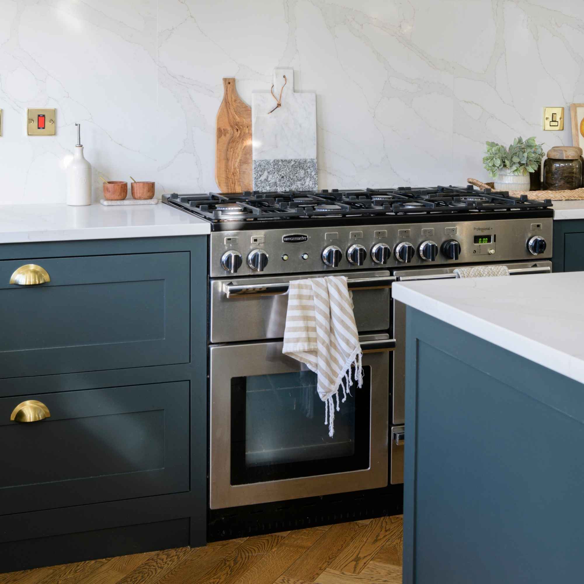 A stainless steel range cooker between dark blue kitchen cabinets, illustrating an oven-door assembly rather than a panel-removal procedure.